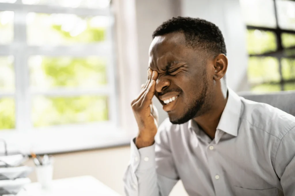 a man suffering from eye pain and holding his hand to his eye