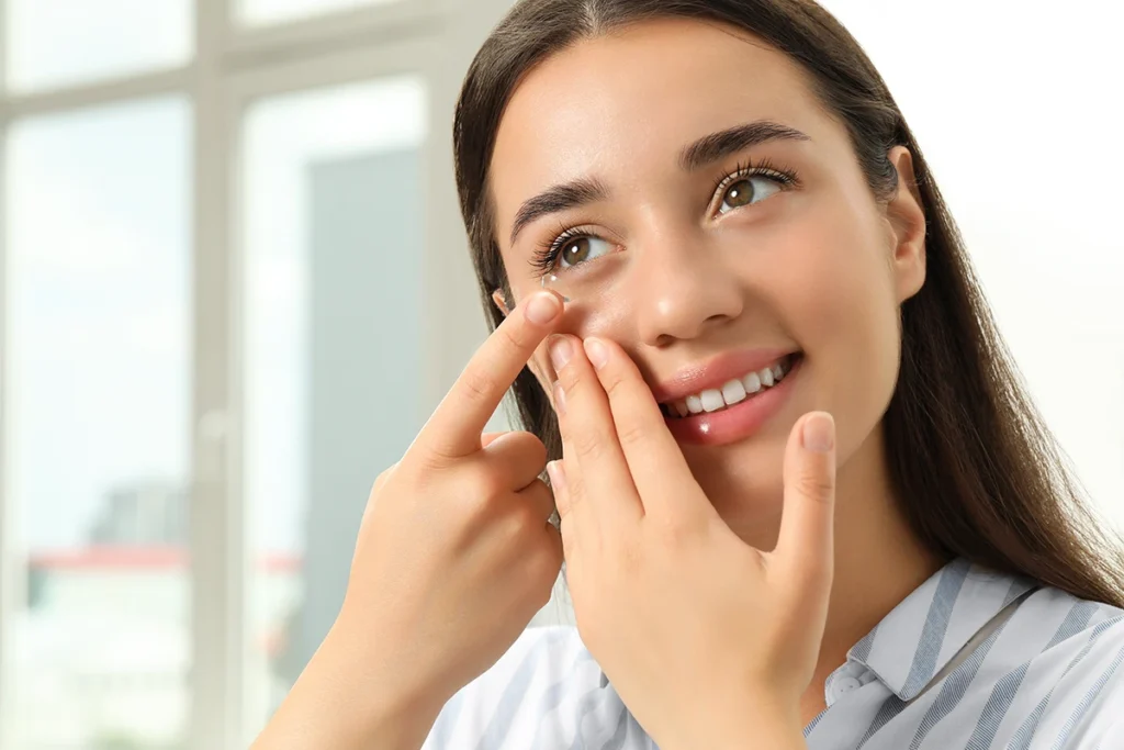 a woman smiling and putting in a contact lens