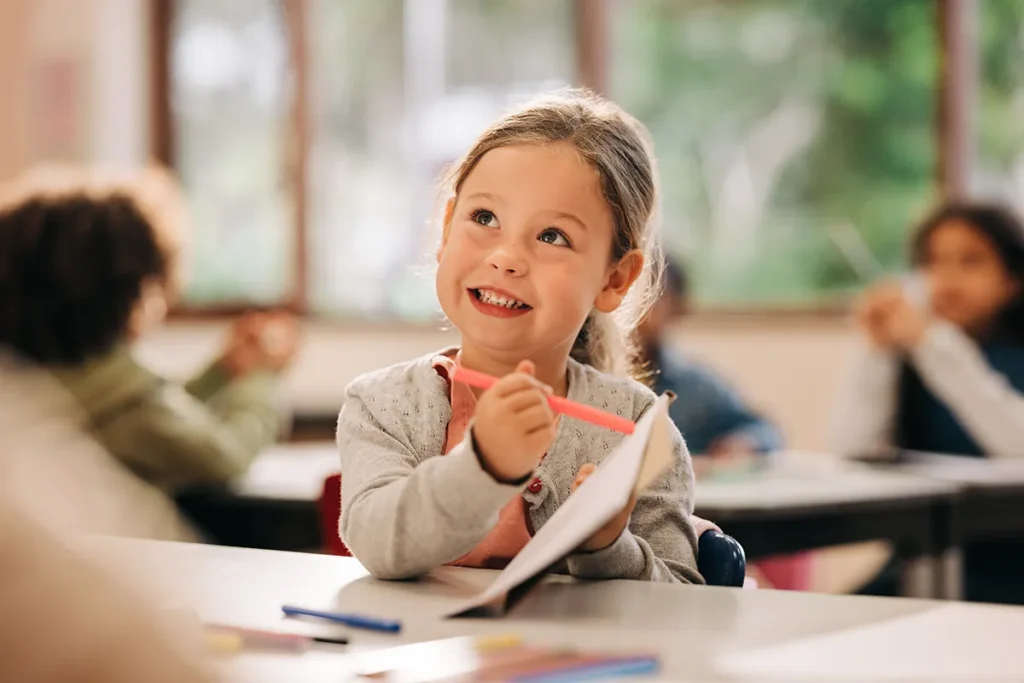 A little girl smiling and learning to draw at school.