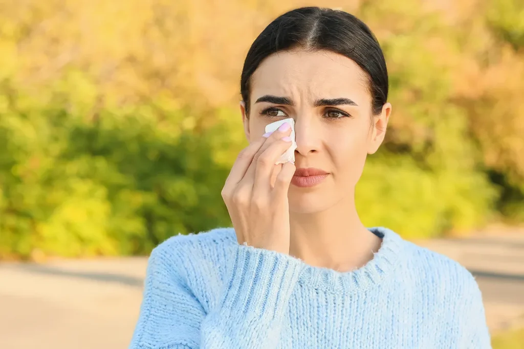 a woman outside wiping her teary eye with a tissue