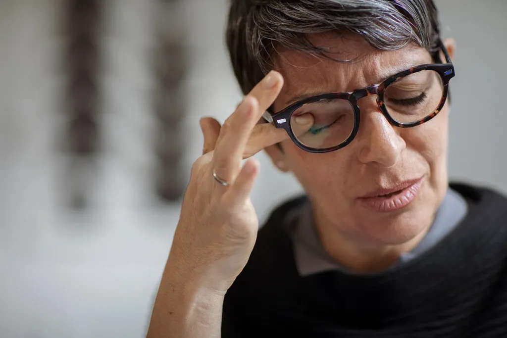 a woman looking stressed and rubbing her eye