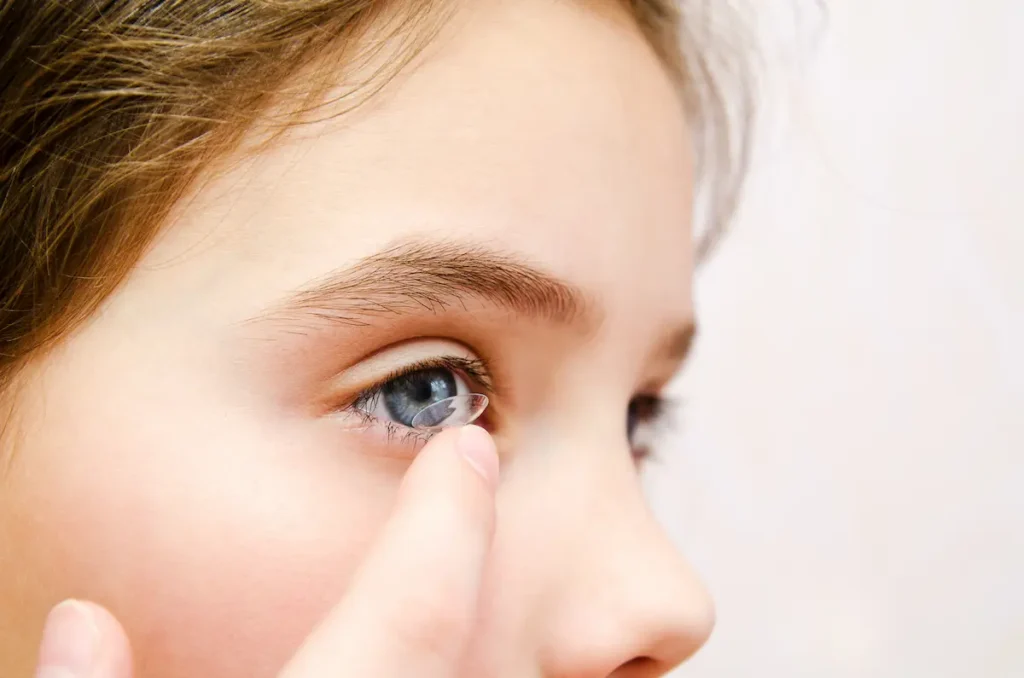 Child placing contact lens into her eye